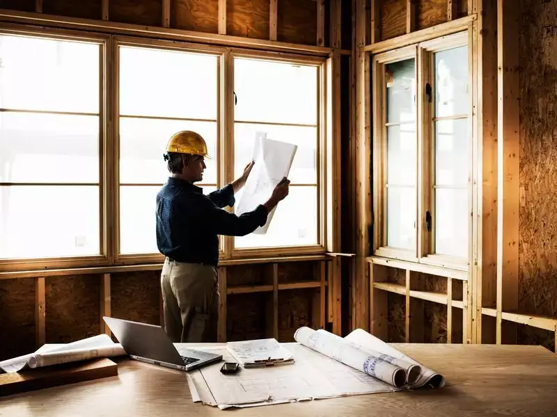 Builders Wanaka Contact Us - Architect reviewing blueprints indoors